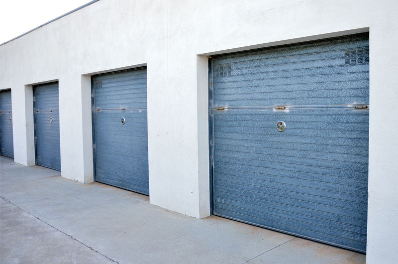 A line of blue storage unit doors set into a grey concrete facade.